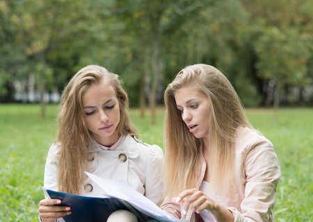 two beautiful female students in a park on the grass