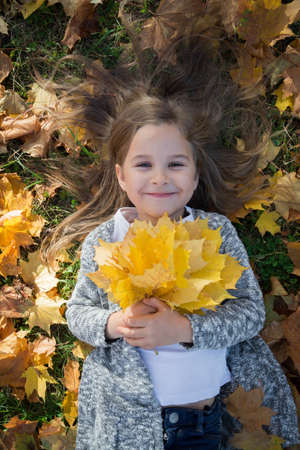 autumn love abstract: portrait little cute girl and yellow leaves background, child timeの写真素材