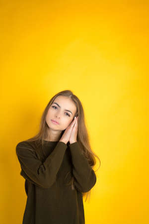 Sleepy young woman on yellow color background wall, studio shotの写真素材