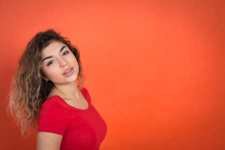 positive girl on a red background in a red t-shirt looks into the camera