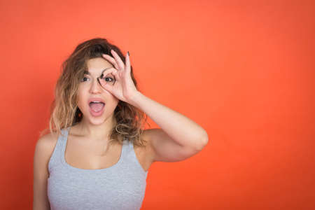Positive young woman gesture and looking in camera, red background, studio shotの写真素材