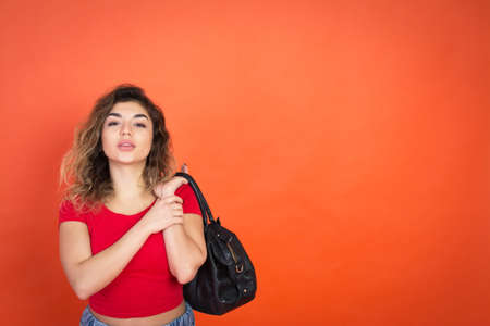 shopping abstract, studio shot, red background and portrait pretty woman with a black bag in hand