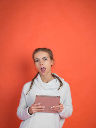 Pretty young woman with tablet over red backgroundの写真素材