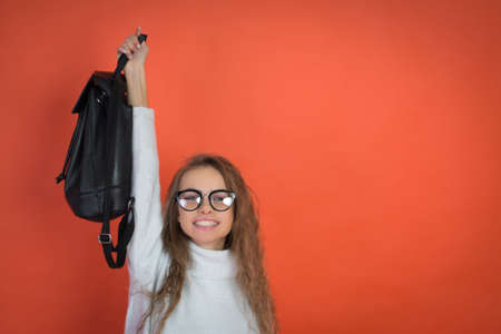 portrait of a cute girl with glasses on a red background and a bag in his hands