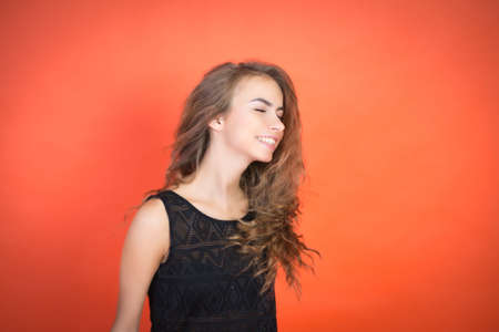 Fashionable young girl posing in the studio on a red background and looking at the camera