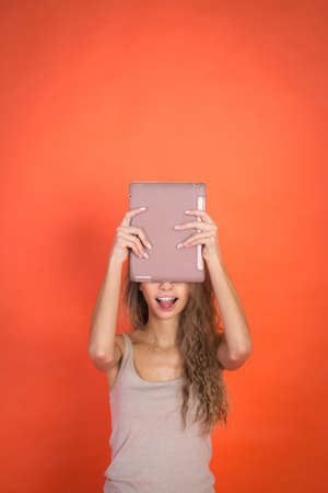 Beautiful young girl with tablet pc on red background