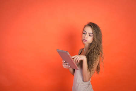 Close up Portrait young beautiful attractive girl looking on digital tablet pc, red backgroundの写真素材