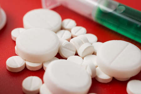 Disease treatment abstract: the pills on red background
