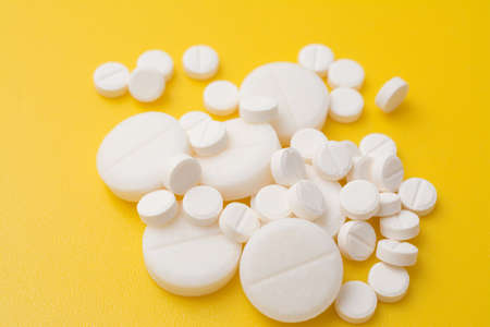 The antibiotic pills dose on a yellow background closeup