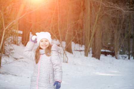 Funny little girl having fun in beautiful winter park during snowfall, happy time conceptの写真素材