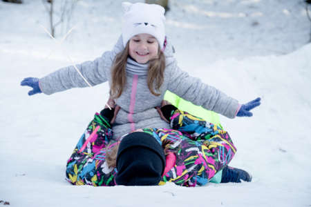 Stylish young mother playing with her little cute daughter in winter snow parkの写真素材