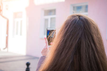 Tourist girl with long dark hair takes pictures of the street architecture of Minsk capital of Belarusの写真素材