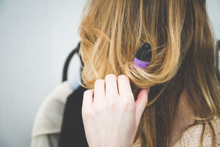 Beuty and fashion concept, Hairdresser curling woman hair with electric iron curler tong, blonde hairの写真素材