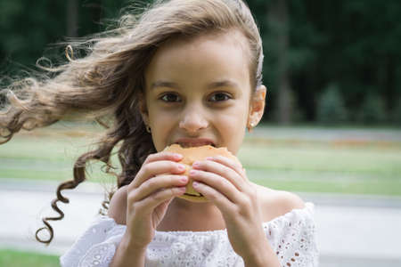 Cute little girl eating fast food hamburgerの写真素材