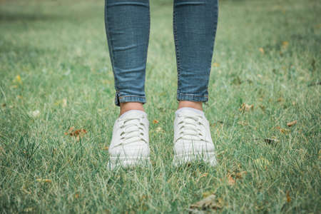 Female feet in jeans and white sports shoesの写真素材