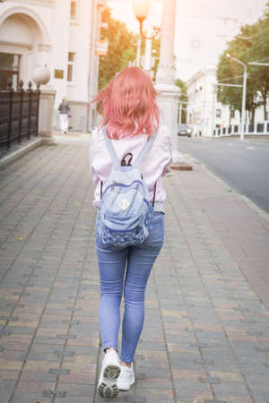 Young student girl walking down the city street with a backpack, in the middle of the roadway, lifestyle conceptの写真素材