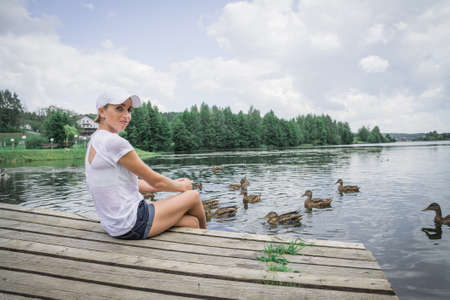Woman Feeding Ducks in city pond a summer dayの写真素材