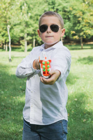 Beautiful eight-year-old boy with a toy gun is photographed in the autumn or summer park.