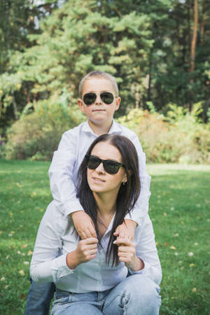 Eight year old son hugs mom in the park on the lawn, family love conceptの写真素材