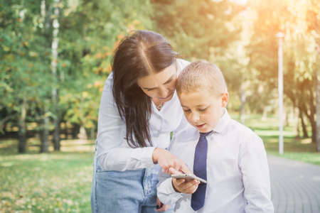 Mom shows her eight-year-old son how to use the mobile app outdoorsの写真素材