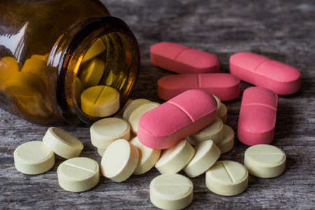 Close up of flu pills on a wooden table, pink and yellow clolors
