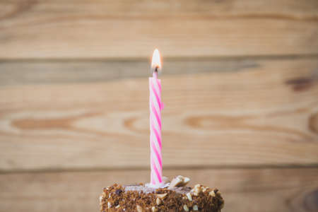 Sponge cake with a burning candle on wooden tableの写真素材