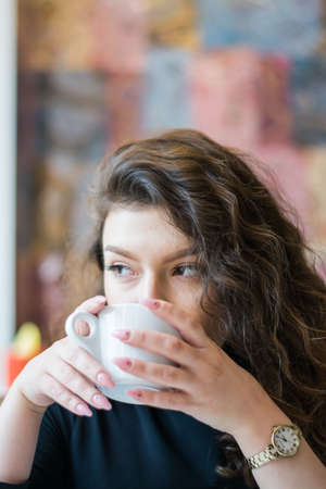 portrait pensive girl in cafe drinks morning coffee indoor