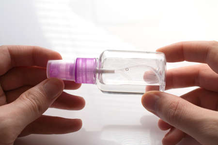 small pink plastic bottle with an antiseptic in hands on a white background