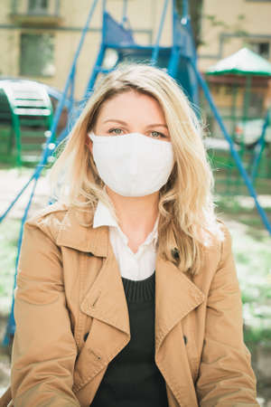 portrait of a blonde woman in a protective face mask outdoorの写真素材