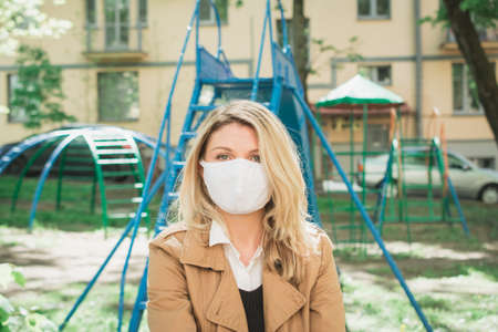 portrait of a blonde woman in a protective face mask outdoorの写真素材