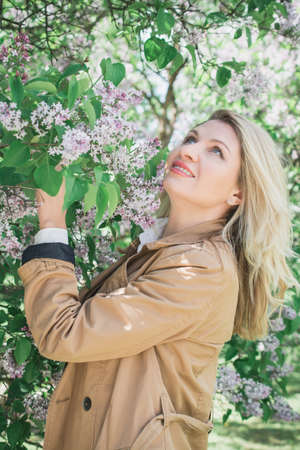 beautiful blonde girl portrait in lilac leaves outdoorの写真素材