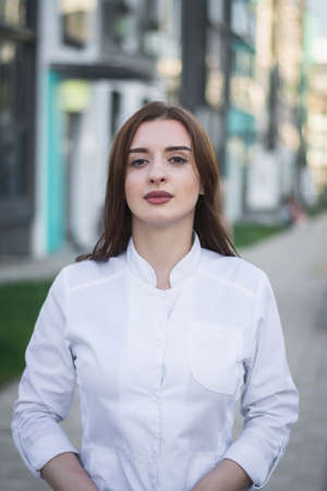 beautiful brunette doctor girl poses for the photographer in a modern residential quarter of her...