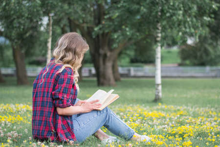 Young pretty woman on the lawn with a book in their hands a summer dayの写真素材