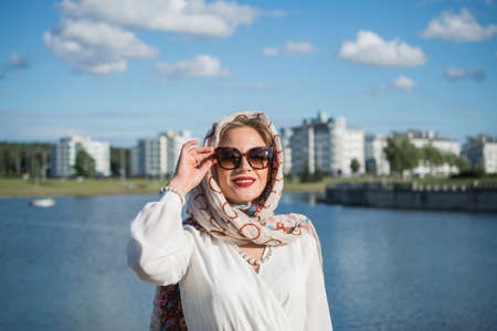 elegant portrait of young woman in headscarf and long white dress outdoor