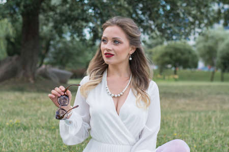 sensitive portrait of an elegant girl in a park on the lawn in the summer