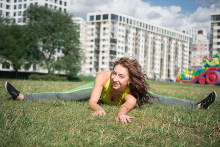 Sport woman doing lawn exercises and stretching on the grass out