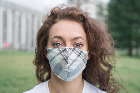 young woman wearing facial mask for virus protection standing outdoors