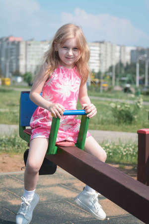 Girl child ride on a swing in a city parkの写真素材