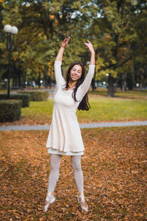 Beautiful girl ballerina posing for photographer in autumn parkの写真素材