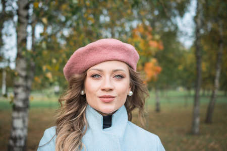 Beautiful girl in a blue coat and beret in an autumn parkの写真素材