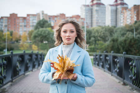 Portrait of a beautiful girl in the autumn city parkの写真素材