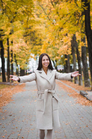 elegant brunette girl on footpath in city park in autumn timeの写真素材