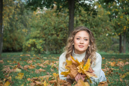 An elegant girl in autumn clothes is photographed in an autumn parkの写真素材