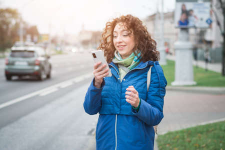Beautiful girl with a phone in her hands on a city streetの写真素材
