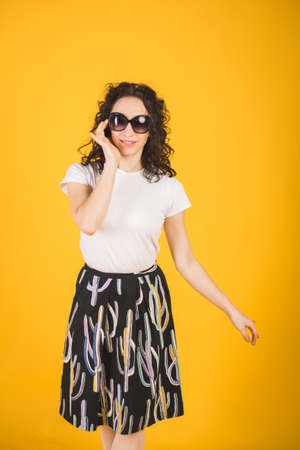 Stylish beautiful girl portrait on a yellow background with a phone in his handsの写真素材