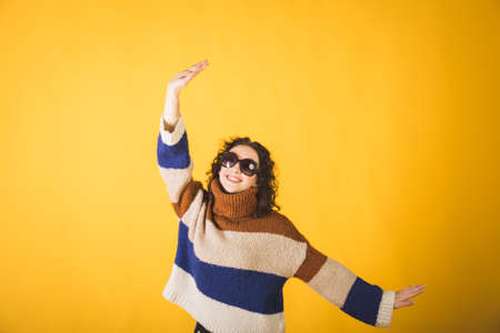 Beautiful young hipster girl in a striped sweater on a yellow backgroundの写真素材