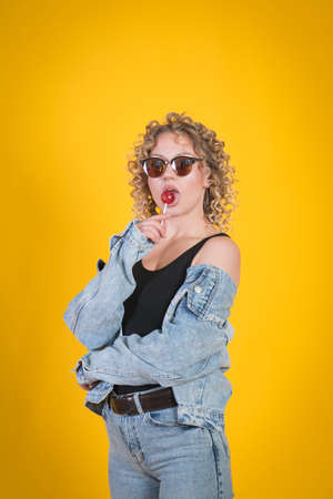 Cute Girl Holding Lollipop Against Yellow Background