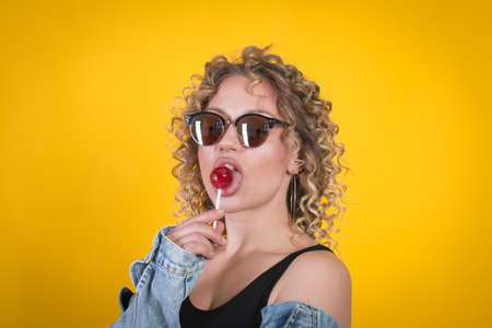 Cute Girl Holding Lollipop Against Yellow Background