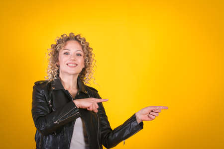 Stylish girl in a black leather jacket on a yellow backgroundの写真素材