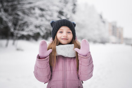 Beautiful little girl five years old portrait in a snowy city park in winterの写真素材